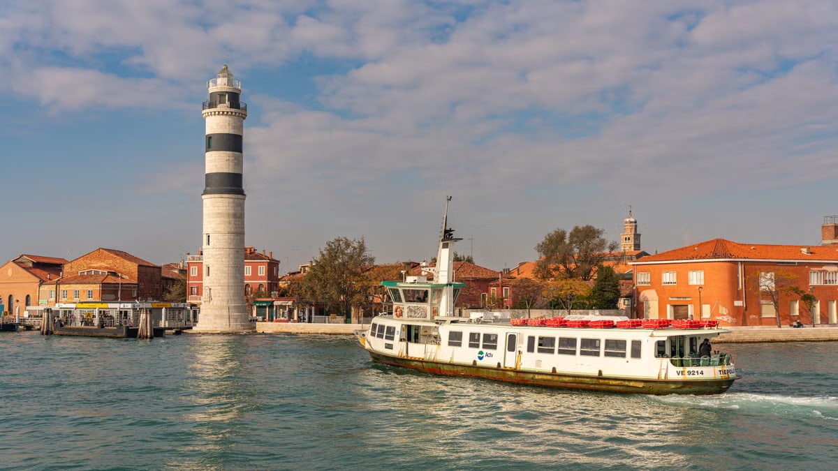 Charming view of Murano with lighthouse and ferry sailing through Venetian waters.